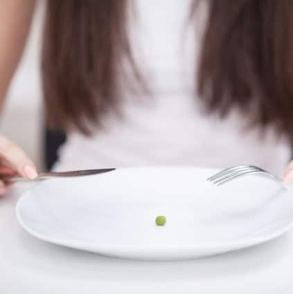 A woman eats a pea as part of her pica eating disorder treatment